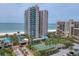An aerial view of resort-style living: tennis courts, pools, beachfront access, and high-rise buildings at 1520 Gulf Blvd # 404, Clearwater, FL 33767