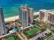 Aerial view showcasing the beachfront condo, swimming pool, tennis courts, and manicured landscaping at 1520 Gulf Blvd # 404, Clearwater, FL 33767