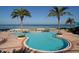Beautifully landscaped pool area with palm trees, lounge chairs, and direct access to the sandy beach at 1520 Gulf Blvd # 404, Clearwater, FL 33767