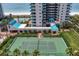 Aerial view of tennis court nestled next to tropical trees and the ocean at 1520 Gulf Blvd # 404, Clearwater, FL 33767
