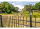 Scenic view of a serene pond, partially obscured by shrubbery, surrounded by a black metal fence at 17205 Tiffany Shore Dr, Lutz, FL 33549