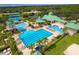 Aerial view of a community pool with lap lanes, a splash pad, shaded seating, and lush landscaping at 19246 Meadow Pine Dr, Tampa, FL 33647
