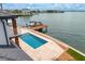 Aerial view of the waterfront pool, dock with boat lift, and manicured yard at 2250 Donato Dr, Belleair Beach, FL 33786