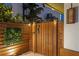 Stylish wooden gate accented with a seahorse knocker, lush vertical garden, and integrated landscape lighting at 2250 Donato Dr, Belleair Beach, FL 33786