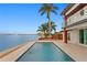 Waterfront pool area features a modern deck, palm trees, and stunning water views at 2250 Donato Dr, Belleair Beach, FL 33786