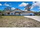 Exterior shot showing the front of the house with a 2 car garage, long driveway and shade tree at 2360 Sutton Pl, Spring Hill, FL 34608