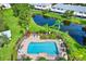 Aerial view of a community pool surrounded by palm trees, with a pond in the background at 26514 Chimney Spire Ln, Wesley Chapel, FL 33544