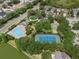 Aerial view showcasing a heart-shaped community pool, tennis court, playground and mature trees in a residential area at 32201 Brookstone Dr, Wesley Chapel, FL 33545