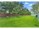 Large backyard boasts mature trees, lush grass, and a brick wall, offering privacy and a serene outdoor space at 32201 Brookstone Dr, Wesley Chapel, FL 33545