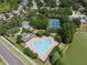 Aerial view of community pool with lounge chairs, a tennis court, and a playground in a lush, green setting at 32201 Brookstone Dr, Wesley Chapel, FL 33545