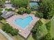Overhead view of a heart-shaped community pool surrounded by lounge chairs, lush trees, and tables for relaxation at 32201 Brookstone Dr, Wesley Chapel, FL 33545