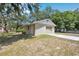 Detached garage with a concrete driveway and an aged rollup door and side door at 34125 Chancey Rd, Wesley Chapel, FL 33543