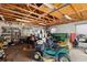 Garage interior full of mowers and tools and with an exposed wooden ceiling at 34125 Chancey Rd, Wesley Chapel, FL 33543