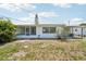 Rear exterior of the home showcasing the screen patio, windows, and a small, partially bare lawn at 3813 Luma Dr, Holiday, FL 34691