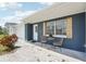 A cozy front porch features chairs, a small table, and decorative shutters near a well-manicured lawn at 3813 Luma Dr, Holiday, FL 34691