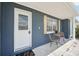 Charming front porch with dark blue painted brick, shutters, seating and white trim at 3813 Luma Dr, Holiday, FL 34691