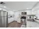 Bright kitchen featuring stainless steel appliances, white cabinetry, granite countertops, and wood flooring at 3813 Luma Dr, Holiday, FL 34691