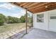 Outdoor patio with a concrete tile floor and a partial view of the green lawn and trees in the backyard at 3813 Luma Dr, Holiday, FL 34691
