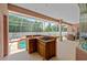 Covered outdoor kitchen features a cooktop, sink, and bar area next to the pool at 4022 Valrico Grove Dr, Valrico, FL 33594