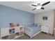 Charming bedroom with blue accent wall, ceiling fan, and white furniture including a bed and shelving unit at 4915 Pennsbury Dr, Tampa, FL 33624