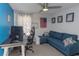 A bright room with blue accent wall, equipped with a desk, chair, couch, and ceiling fan, ideal for an office space at 4915 Pennsbury Dr, Tampa, FL 33624