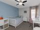 Bedroom with blue accent wall, ceiling fan, white bed and desk with pink chair at 4915 Pennsbury Dr, Tampa, FL 33624