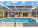 A private screened-in pool with an outdoor shower, lush landscaping, and view to the main living areas at 4915 Pennsbury Dr, Tampa, FL 33624