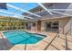 A private screened-in pool with an outdoor shower, lush landscaping, and view to the dining room at 4915 Pennsbury Dr, Tampa, FL 33624