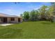 Spacious backyard featuring lush green grass, mature trees, and a privacy fence at 5193 Higate Rd, Spring Hill, FL 34609
