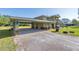 Wide view of a home with a spacious driveway leading to a covered garage, surrounded by a green lawn at 592 Ken Hubbard Rd, Terra Ceia, FL 34250