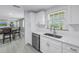 Bright kitchen with white cabinets, a stainless steel dishwasher, and dining area access at 592 Ken Hubbard Rd, Terra Ceia, FL 34250