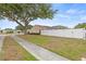 Side view of the home showcasing the fenced yard, well-maintained lawn, and mature landscaping at 6507 61St E Dr, Palmetto, FL 34221