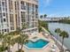 Condo featuring a community pool and spa overlooking waterfront views, along with outdoor seating and beautiful landscaping at 7400 Sun Island S Dr # 206, South Pasadena, FL 33707