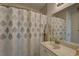A tiled bathroom features a large mirror, neutral shower curtain, and a clean, modern vanity at 8358 Candlewood Rd, Seminole, FL 33777