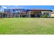 Large backyard with green grass, a screened-in lanai, and views of the surrounding landscape at 8474 Dunham Station Dr, Tampa, FL 33647