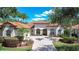 Charming single-story home featuring a tile roof, arched windows, and a brick-paved driveway framed by manicured landscaping at 8474 Dunham Station Dr, Tampa, FL 33647