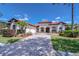 Beautiful single-story home with tile roof, arched windows, three-car garage, and landscaped brick-paved driveway at 8474 Dunham Station Dr, Tampa, FL 33647