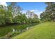 Lush backyard featuring a serene canal view, mature trees, and manicured lawn at 8600 Village Mill Row, Hudson, FL 34667