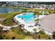 Aerial view of a resort-style community pool, clubhouse, and well manicured lawn with palm trees at 11504 Sage Canyon Dr, Riverview, FL 33578