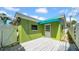 Home's backyard with a painted wooden deck and a bright green exterior at 121 86Th Ter, Treasure Island, FL 33706
