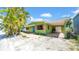 Charming home with a vibrant green exterior, red shutters, blue door, and a covered carport, surrounded by lush trees at 121 86Th Ter, Treasure Island, FL 33706