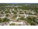 Wide aerial view showcasing a community of single-story homes amid lush greenery, roads, and waterways at 1472 Mission Hills Blvd # 24F, Clearwater, FL 33759