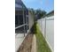 View of the side yard of a home with a screened patio and a white privacy fence at 1765 Oak Pond Ct, Oldsmar, FL 34677
