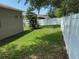 Green backyard with a decorative tree along the side of the house and a white fence at 1765 Oak Pond Ct, Oldsmar, FL 34677