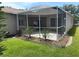 Exterior view of a screened-in patio overlooking a green lawn with garden beds at 1765 Oak Pond Ct, Oldsmar, FL 34677