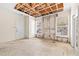 Living room needing repair, featuring exposed ceiling beams, windows, a door, and damaged walls and floor at 18017 Villa Creek Dr # 18017, Tampa, FL 33647