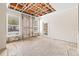 Living room needing repair, featuring exposed ceiling beams, windows, a door, and damaged walls and floor at 18017 Villa Creek Dr # 18017, Tampa, FL 33647
