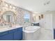 Bright bathroom with floral wallpaper, a soaking tub, and dual vanities with modern fixtures at 18219 Ramble On Way, Land O Lakes, FL 34638