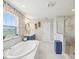 Bright bathroom with marble floors, glass shower, soaking tub, floral wallpaper, and blue vanity at 18219 Ramble On Way, Land O Lakes, FL 34638