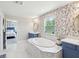 Bright bathroom featuring soaking tub, dual vanities, floral wallpaper and marble tile at 18219 Ramble On Way, Land O Lakes, FL 34638